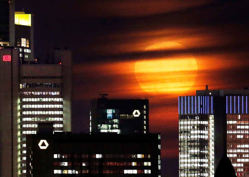 La superluna ligeramente cubierta de nubes mientras se eleva sobre el distrito bancario de Frankfurt, Alemania. Imagen: Michael Probst / AP